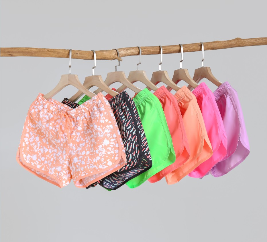 Colourful beach shorts hanging on wooden hangers